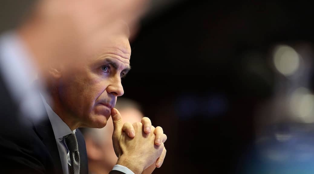 Cab=ndid shot of Mark Carney with his hands clasped in front of gis face and thumb to lip, as he ponders something